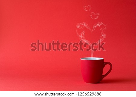 Cup of tea or coffee with steam in one heart shape on red background. Valentine's day celebration or love concept. Copy space Royalty-Free Stock Photo #1256529688