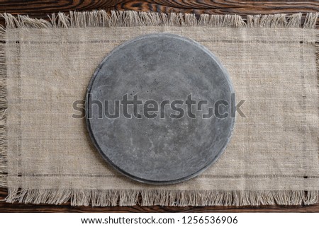 gray concrete round signboard on light linen fabric and wooden brown background Royalty-Free Stock Photo #1256536906