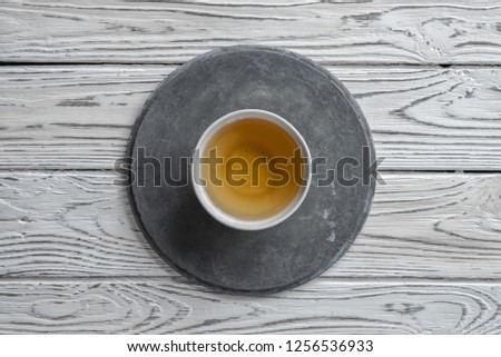 gray concrete round plate on light white wooden  background and a Cup of tea