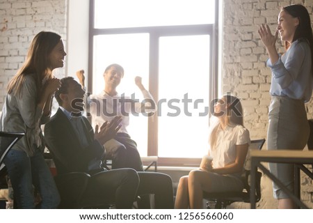 Excited diverse team people applauding celebrating success supporting leader telling great news, happy multi-ethnic employees sales group congratulating colleague with business achievement or reward Royalty-Free Stock Photo #1256566060