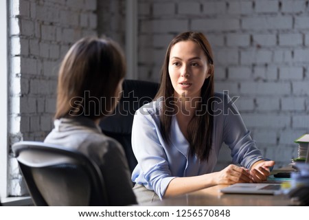 Serious professional female advisor consulting client at meeting talking having business conversation or making offer, insurer giving advice, mentor teaching intern, hr speaking at job interview Royalty-Free Stock Photo #1256570848