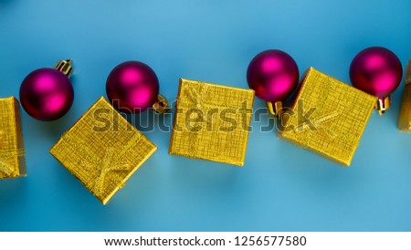 festive purple balls golden gift boxes on a blue background. Christmas composition. Festive background.
