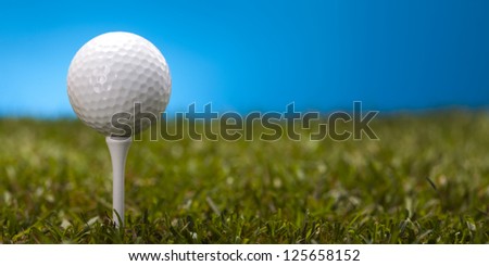 Golf ball on green grass over a blue background