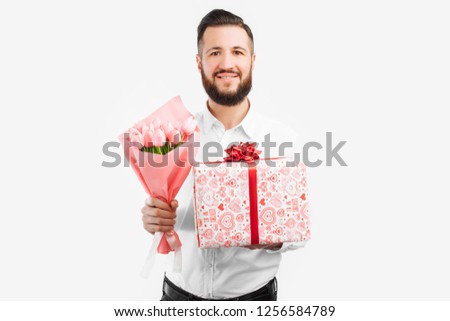 Elegant man with a beard holding a bouquet of tulips and a gift box, a gift for Valentine's Day. On a white background