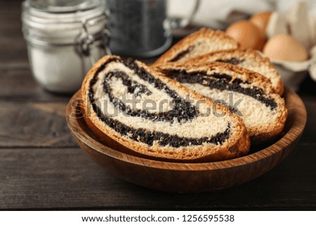 Pieces of tasty sweet bun with poppy seeds on wooden table
