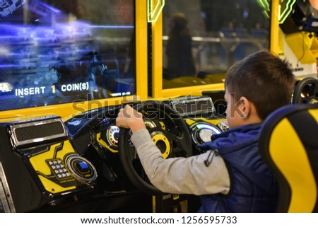 Teenager plays on gaming machine simulator car in the club Royalty-Free Stock Photo #1256595733