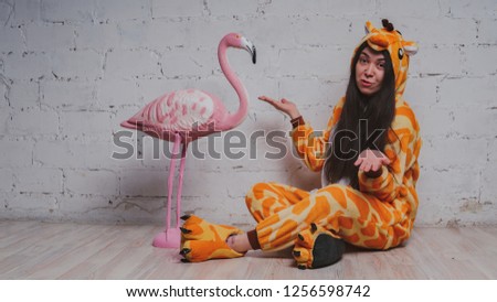 Cheerful and positive girl in children's pajamas as a giraffe. Student in a yellow costume. Concept animator for children's parties.
