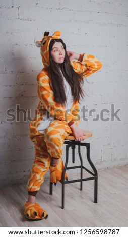 Cheerful and positive girl in children's pajamas as a giraffe. Student in a yellow costume. Concept animator for children's parties.
