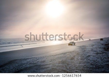 Daytona beach with silhouette of people and cars riding on the sand