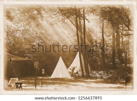 Sepia colored old style photo of a tent campground surrounded by trees with light rays streaming onto it.