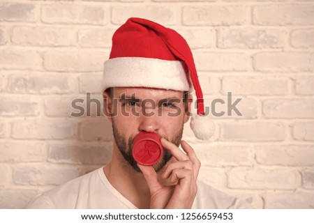 Man hold red jewelry box at bearded face. Gift giving, holiday greeting. Macho in santa hat present on white brick wall. Boxing day concept. Christmas, new year preparation and celebration.