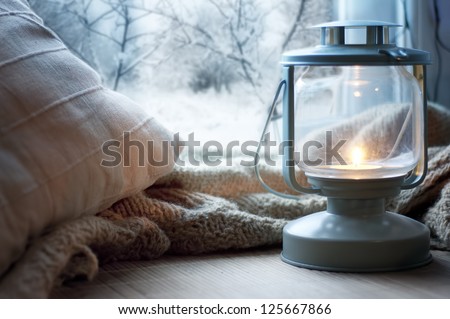 lantern and pillows on windowsill with winter view Royalty-Free Stock Photo #125667866