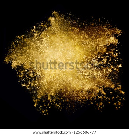 Closeup golden glitter explosion. Dust particle isolated on black. Abstract background. Color explosion