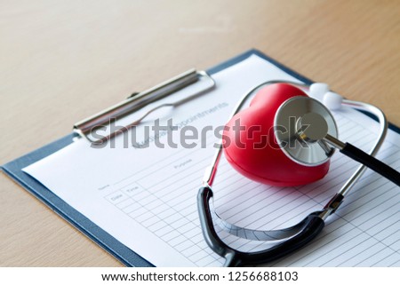 Black stethoscope puts on red heart as pretend to examine/check heart with medical appointment sheet. Heath care/medical concept Royalty-Free Stock Photo #1256688103