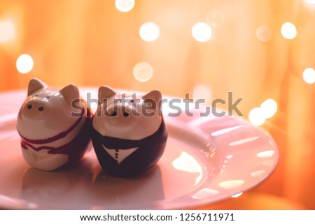 Symbol of the year of the pig on the background of bokeh garlands. Capacity for salt and pepper. Festive table decoration