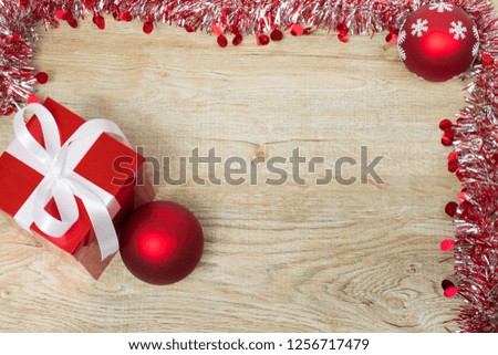 Christmas gift box and red balls on wooden background top view. Happy New Year.