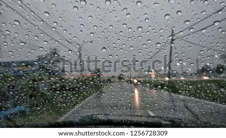 Background is blurred, raindrops on the windscreen to car. 