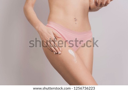 Female applying cosmetic cream for cellulite on her body