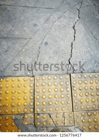 top view earthquake damage pathway surface texture, broken yellow braille brick background, cracked concrete floor