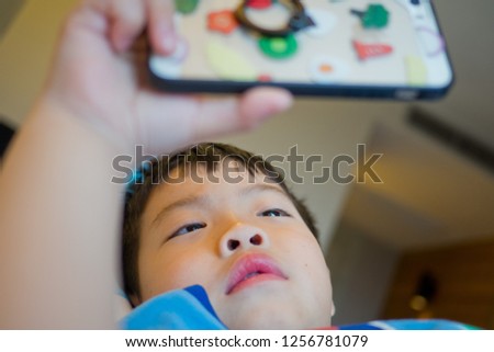 asian chinese boy playing smartphone on bed, watching smartphone, kid use phone and play game, child use mobile, addicted game and cartoon
