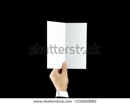 Hand holding blank brochure booklet in the hand. Isolated on black background. Man show offset paper. Sheet template. Book in hands. Booklet folding design. Fold paper sheet display read.
