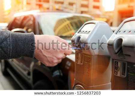 man is paying his parking using credit card at  parking pay station terminal