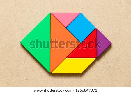 Color tangram puzzle in hexagon shape on wood background