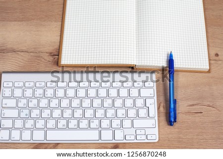 Office desk with blank notebook, computer keyboard and other office supplies