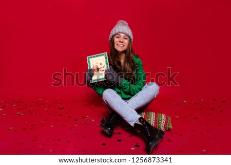 Full-length portrait of lovely  Christmas girl relaxing at christmas party with gifts over confetti and waiting for friends. Indoor shot of adorable girl in green sweater having fun in new year. 