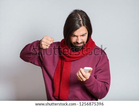handsome bearded man with a fist looks at the phone, closeup over background