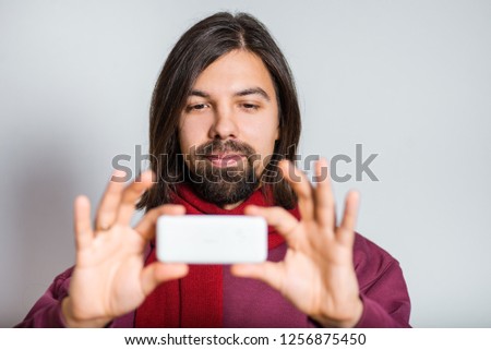 handsome bearded man making funny photo on the phone, closeup over background