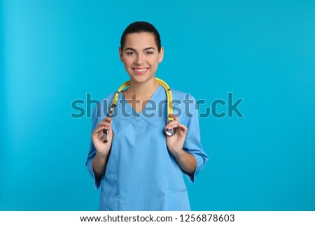 Portrait of young medical assistant with stethoscope on color background