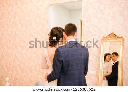 bride and groom are standing by the mirror