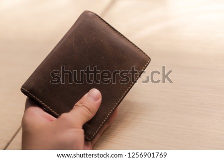 Hand hold brown wallet on wood background. Vintage tone. Money. Royalty-Free Stock Photo #1256901769