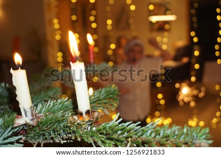 Christmas Green Tree, Candlelight And Blurred Silhouette Of School Boy With  Christmas Cap. Beautiful Festive Background And Close Up. Dark And Light. Burning wax candles.