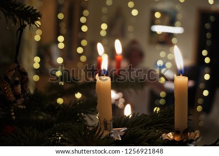 Christmas Green Tree, Candlelight And Blurred Silhouette Of School Boy With  Christmas Cap. Beautiful Festive Background And Close Up. Dark And Light. Burning wax candles.