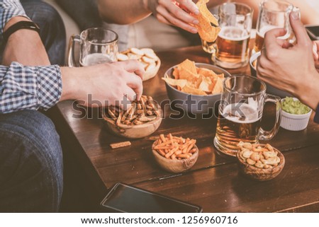 Young people at a beer party with snacks, watching football, toned,