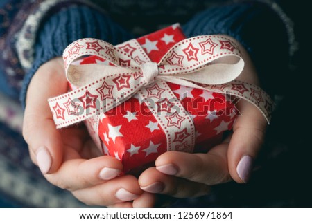 Close up shot of female hands holding a small red gift