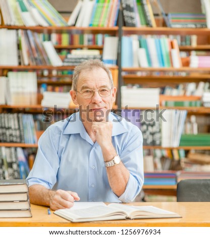 Happy senior man in the library looking at camera