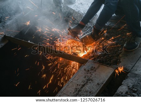 Male worker saws a disk grinding saw armature into a reinforced concrete panel, the destruction of the old house. Sparks from friction with metal. Rescue work.