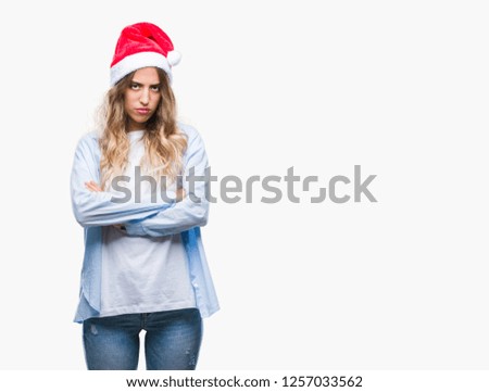 Beautiful young blonde woman wearing christmas hat over isolated background skeptic and nervous, disapproving expression on face with crossed arms. Negative person.