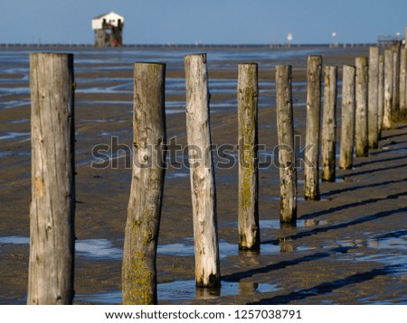 Wooden poles at the beach, buildings in the background in Sankt Peter-Ording