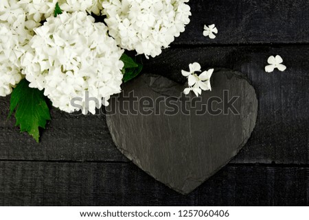 Valentine Day Bouquet flower hydrangea and slate heart on black wooden background. Good morning. Flat lay. Top view. Love. 
