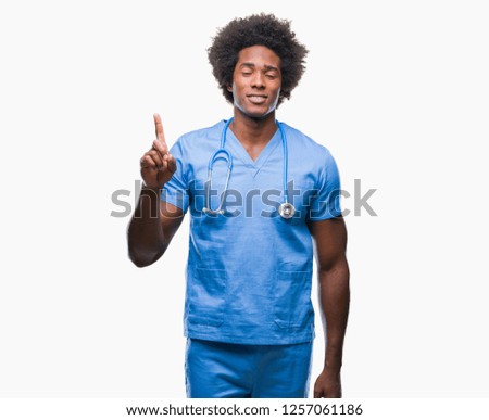 Afro american surgeon doctor man over isolated background showing and pointing up with finger number one while smiling confident and happy.