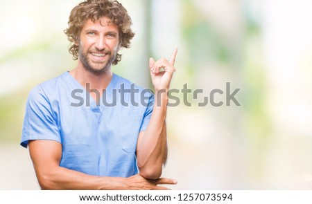 Handsome hispanic surgeon doctor man over isolated background with a big smile on face, pointing with hand and finger to the side looking at the camera.