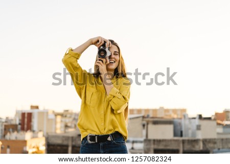 pretty young traveler taking picture with a film camera. girl in a yellow shirt discover a new destination. beautiful woman traveling the world and saving memories