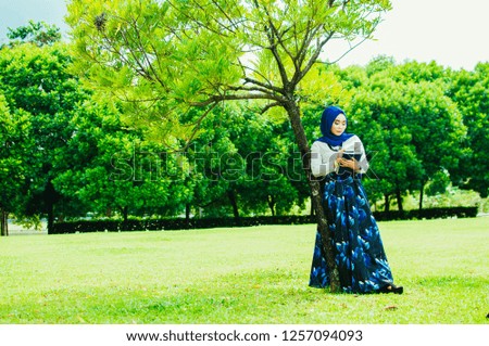 Beautiful Muslim girl with hijab using file walking around the city background. Business woman using phone.