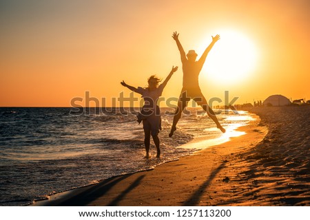 jumping happy cople on tropical sunset