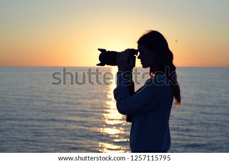 Silhouette of a woman with a camera near the sea                  