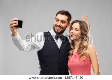 technology and people concept - happy couple in party clothes taking selfie by smartphone over grey background